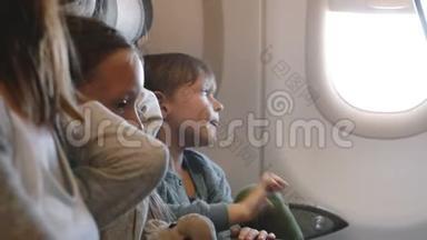 可爱的小男孩很无聊，在长假和家人一起飞行时，在飞机窗口座位上环顾四周。